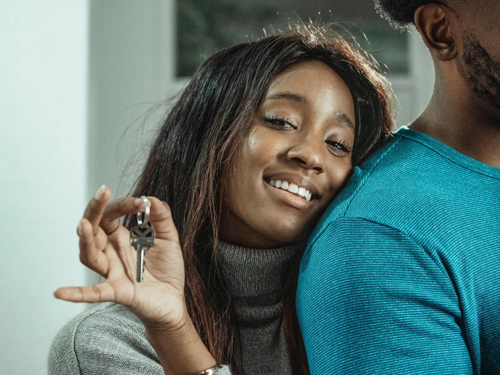 Propriétaires souriants tenant les clés de leur bien.